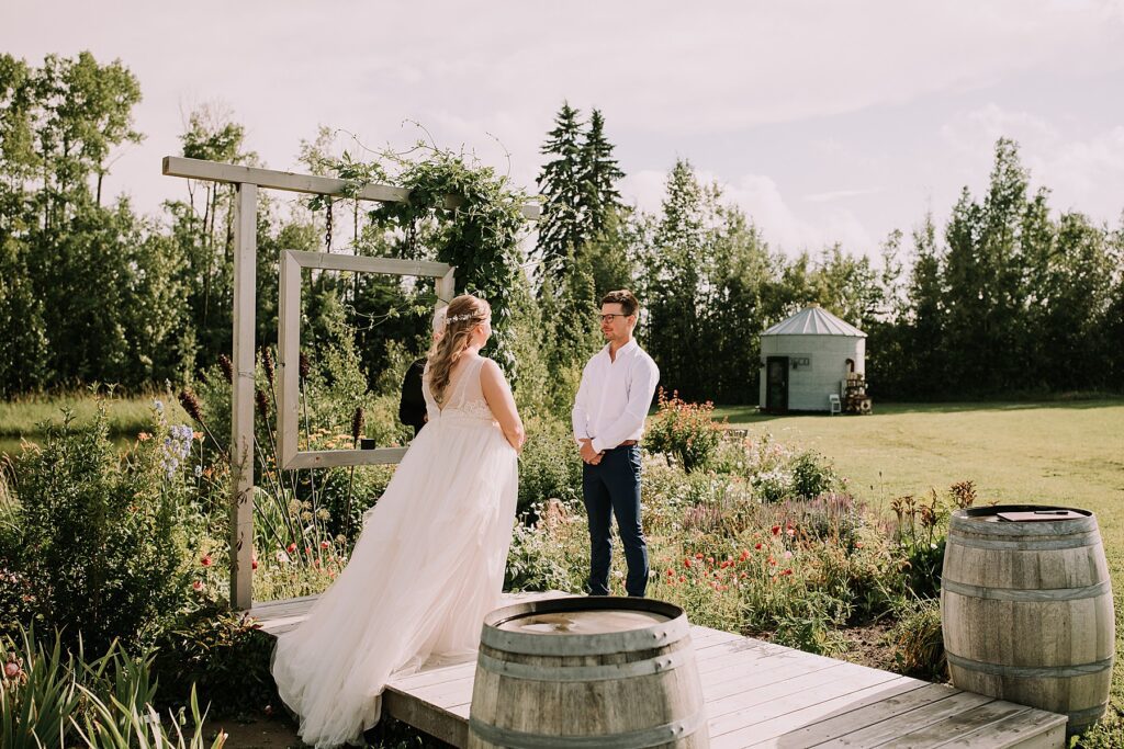 women dressed in a wedding dress and man dressed in dress pants and white shirt. They are standing at the wedding alter surrounded by nature