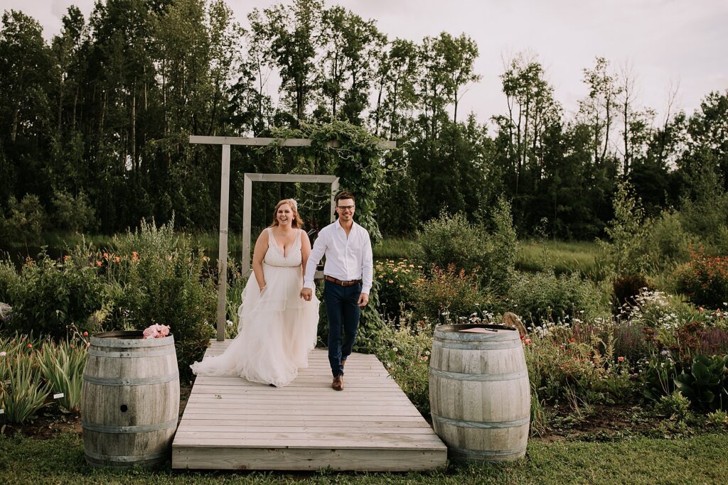 women dressed in a wedding dress and man dressed in dress pants and white shirt. They are standing at the wedding alter surrounded by nature