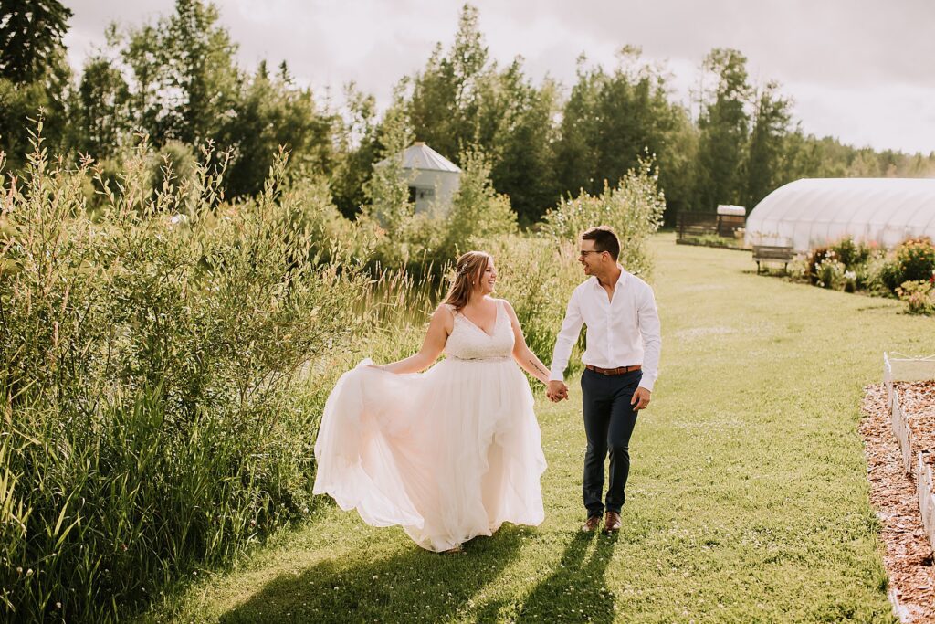 bride and groom standing in nature and snuggling close while posing for wedding photos. 
