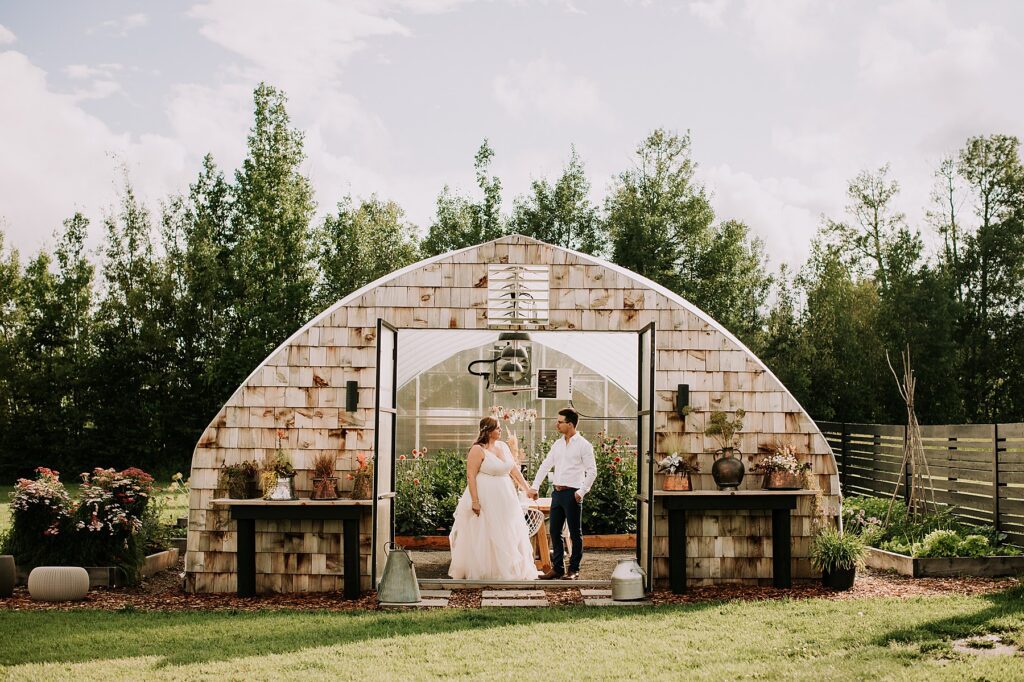 bride and groom standing in nature and snuggling close while posing for wedding photos.