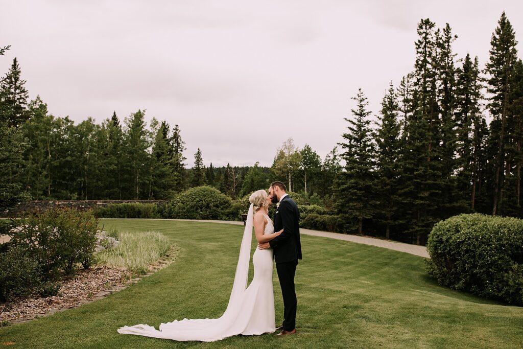 bride and groom romantically posed close together. They are posing for wedding portraits. He is wearing a navy suit and she is wearing a slim fitting dress and veil